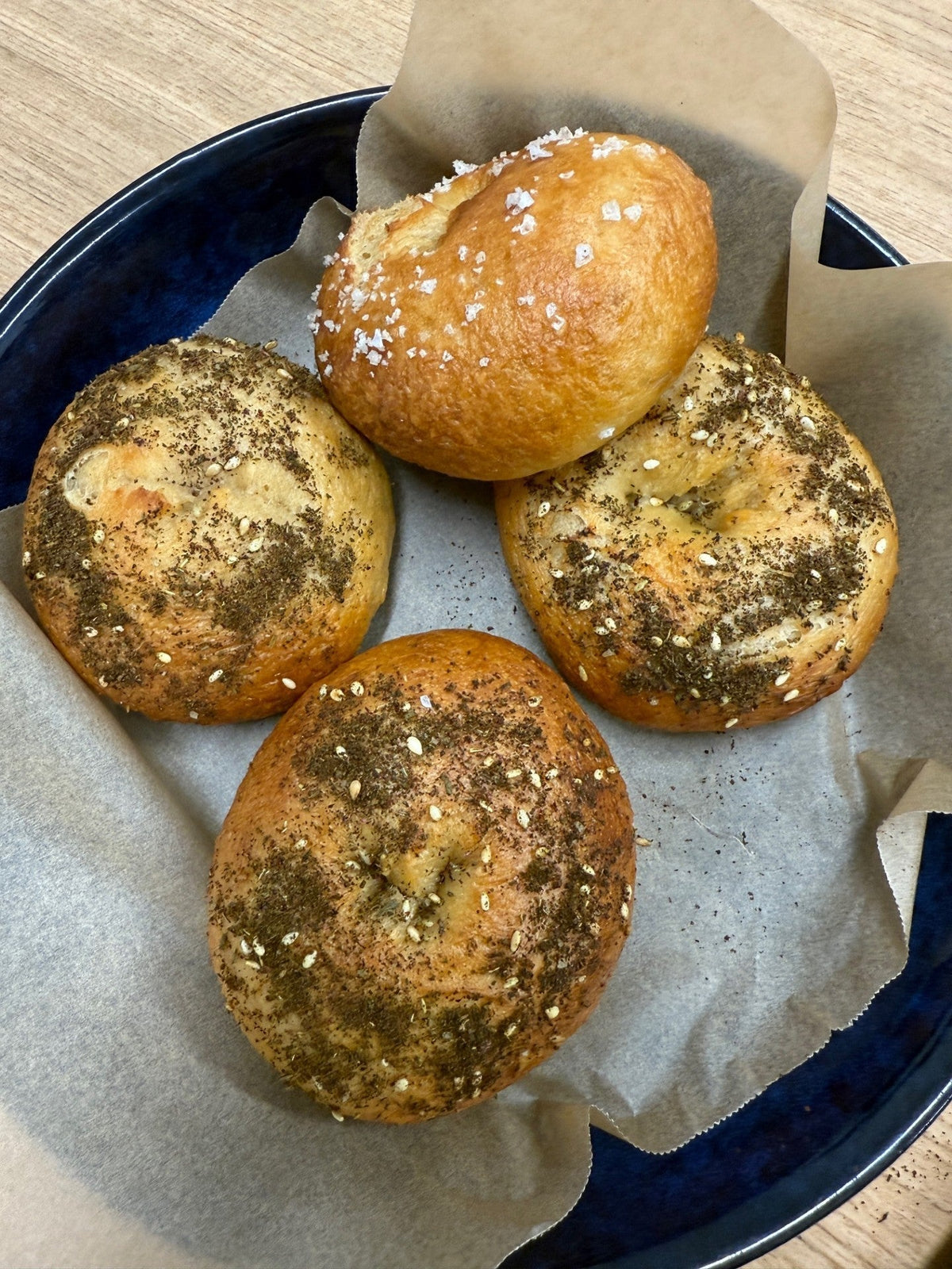 Four seeded lupin flour bagels in a blue bowl lined with baking paper, three topped with everything seasoning and one with salt