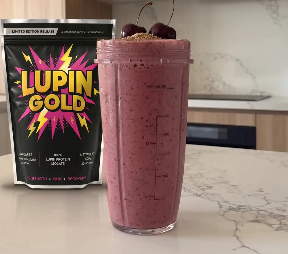 Cherry flax protein smoothie in a blender cup beside a pack of Lupin Gold protein isolate
