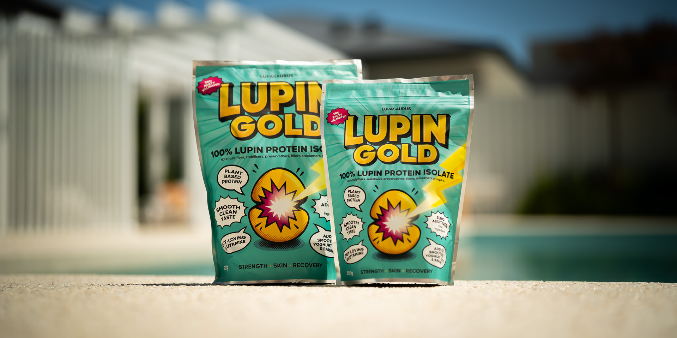 Scoop of unflavoured lupin protein powder being tipped into a blender cup of banana, blueberries and oats beside a Lupin Gold pack