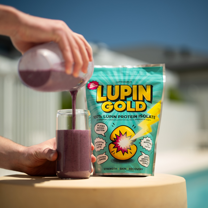 Berry protein smoothie being poured into a glass beside a pack of Lupin Gold lupin protein isolate