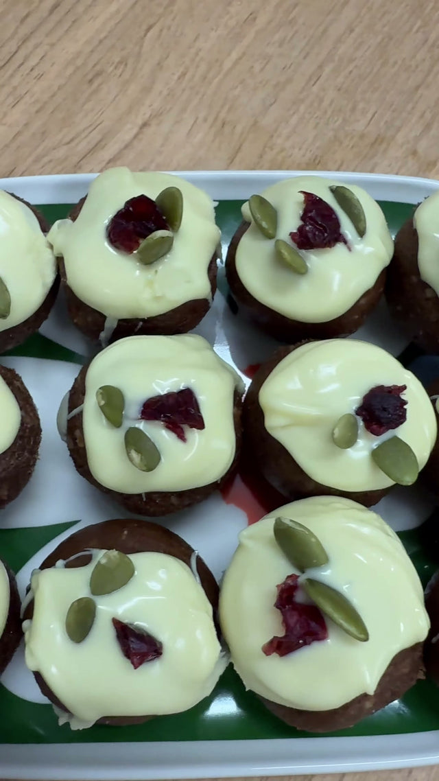 Christmas pudding protein balls topped with white chocolate, dried cranberries and pumpkin seeds on a serving platter