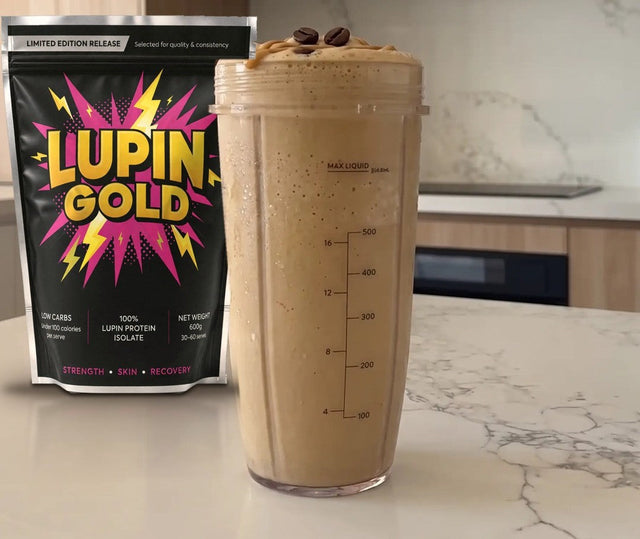Iced coffee peanut butter protein smoothie in a blender cup beside a pack of Lupin Gold protein isolate