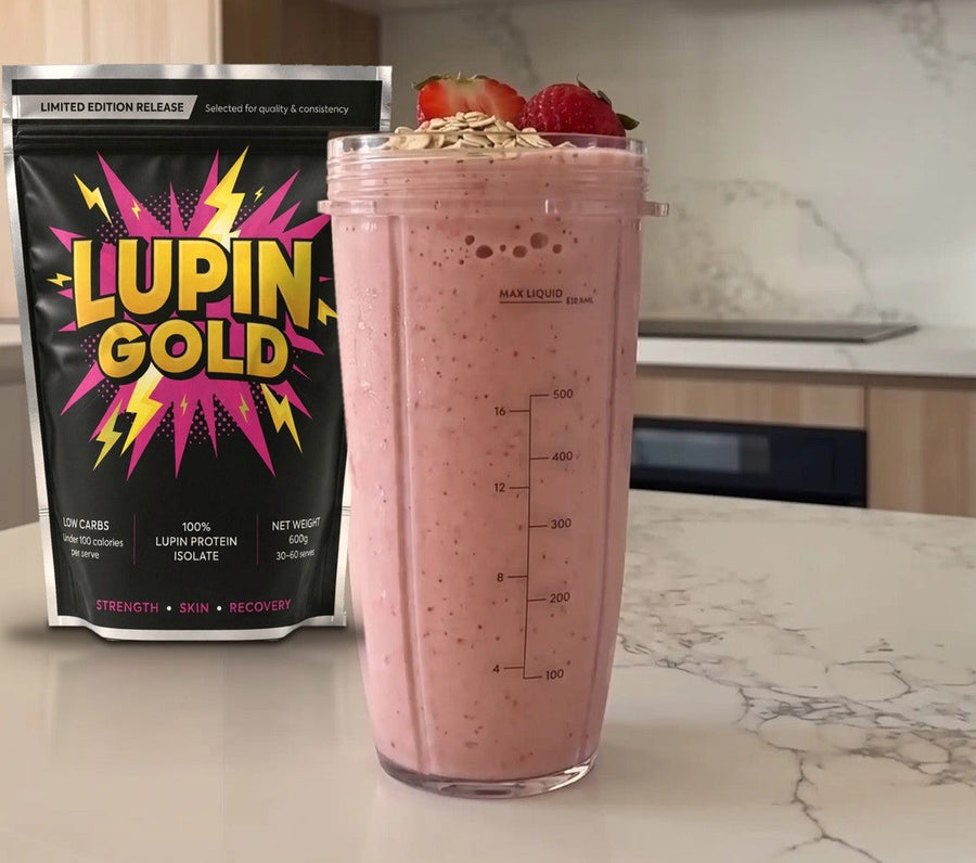 Strawberry oat protein smoothie in a blender cup beside a pack of Lupin Gold protein isolate