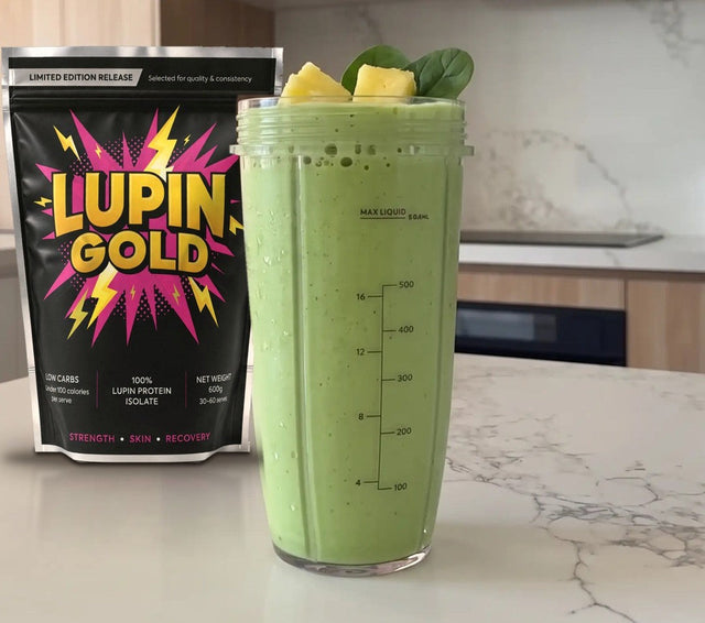 Tropical green protein smoothie in a blender cup beside a pack of Lupin Gold protein isolate