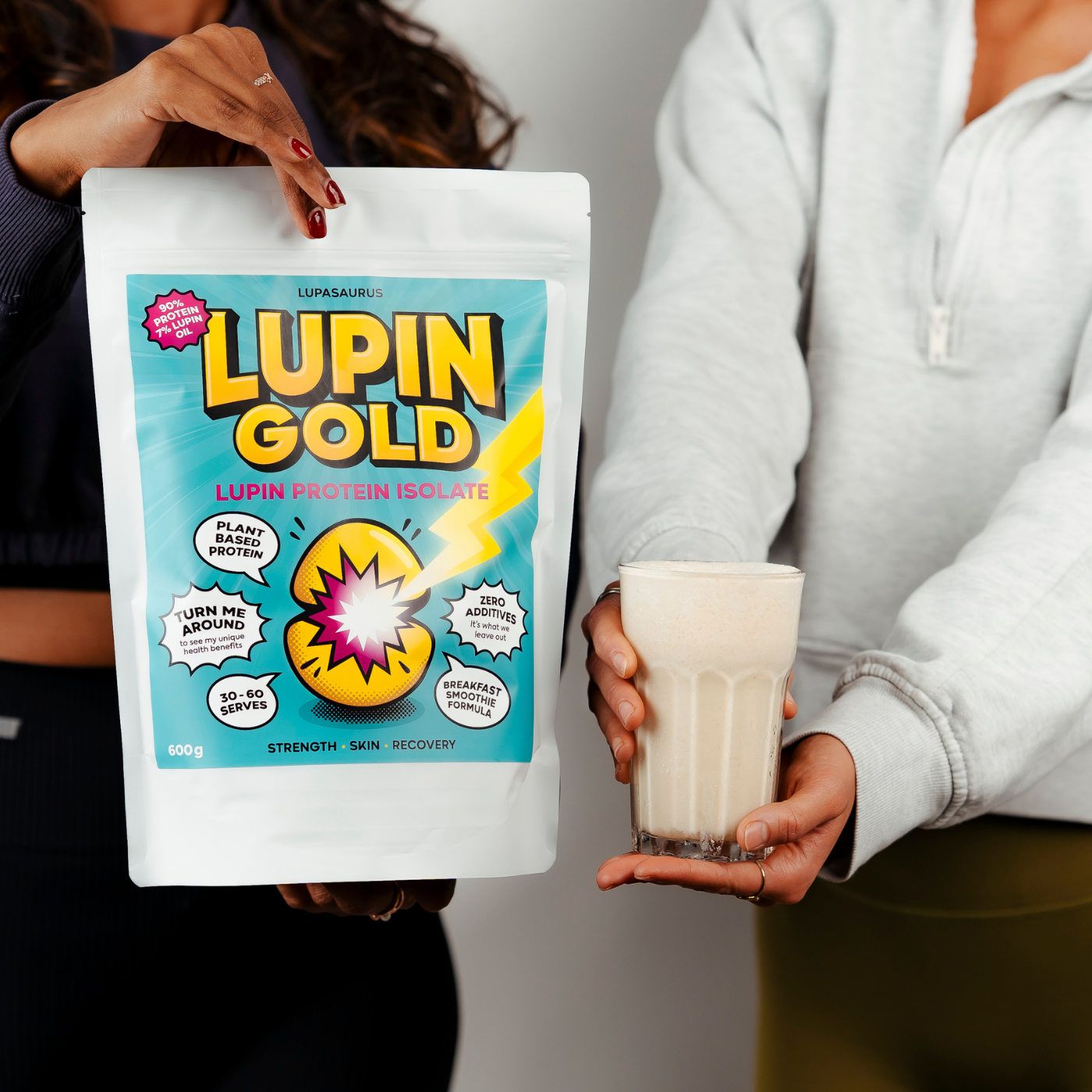 One person holding a packet of Lupin Gold lupin protein isolate and a glass of banana and lupin protein smoothie.