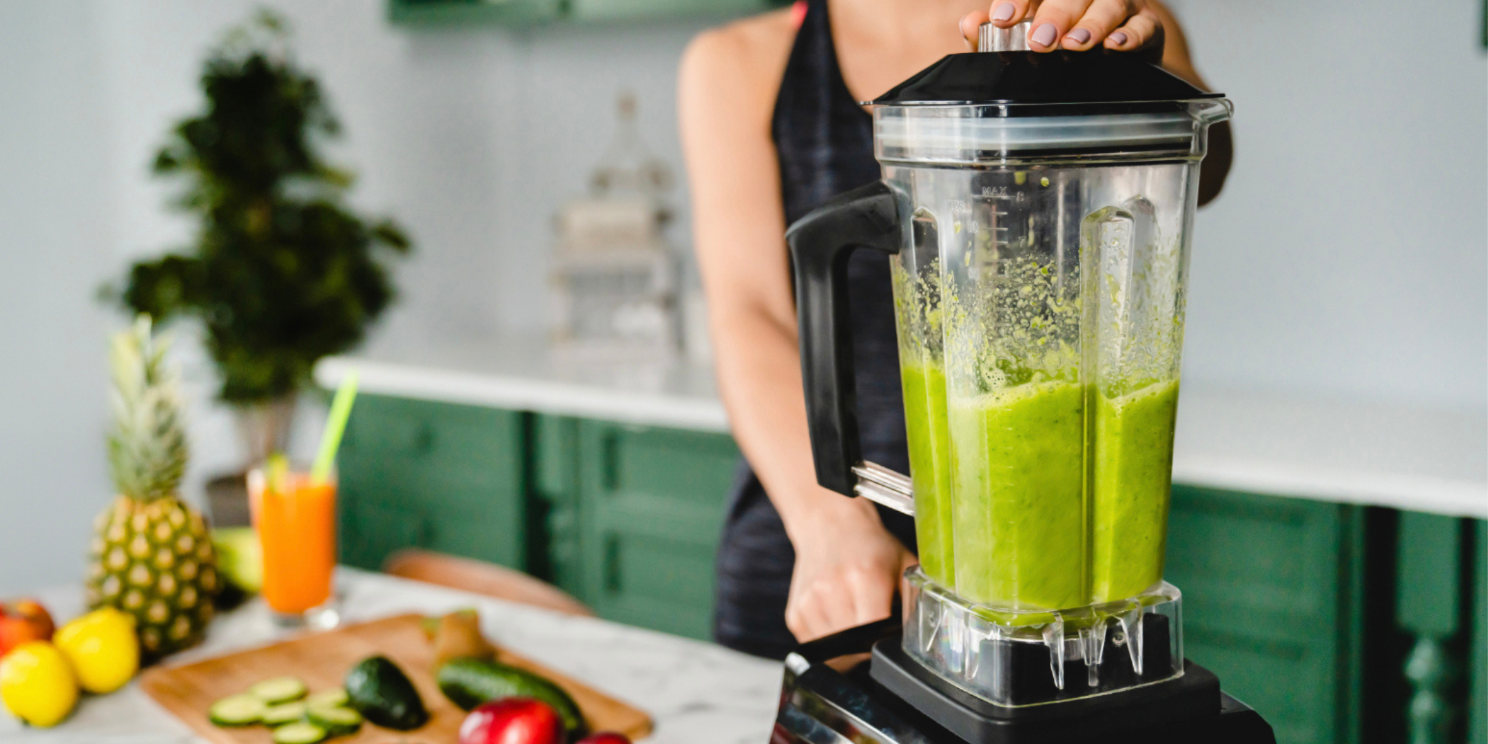Person holding a blender with a green Lupin Gold protein smoothie in a kitchen setting