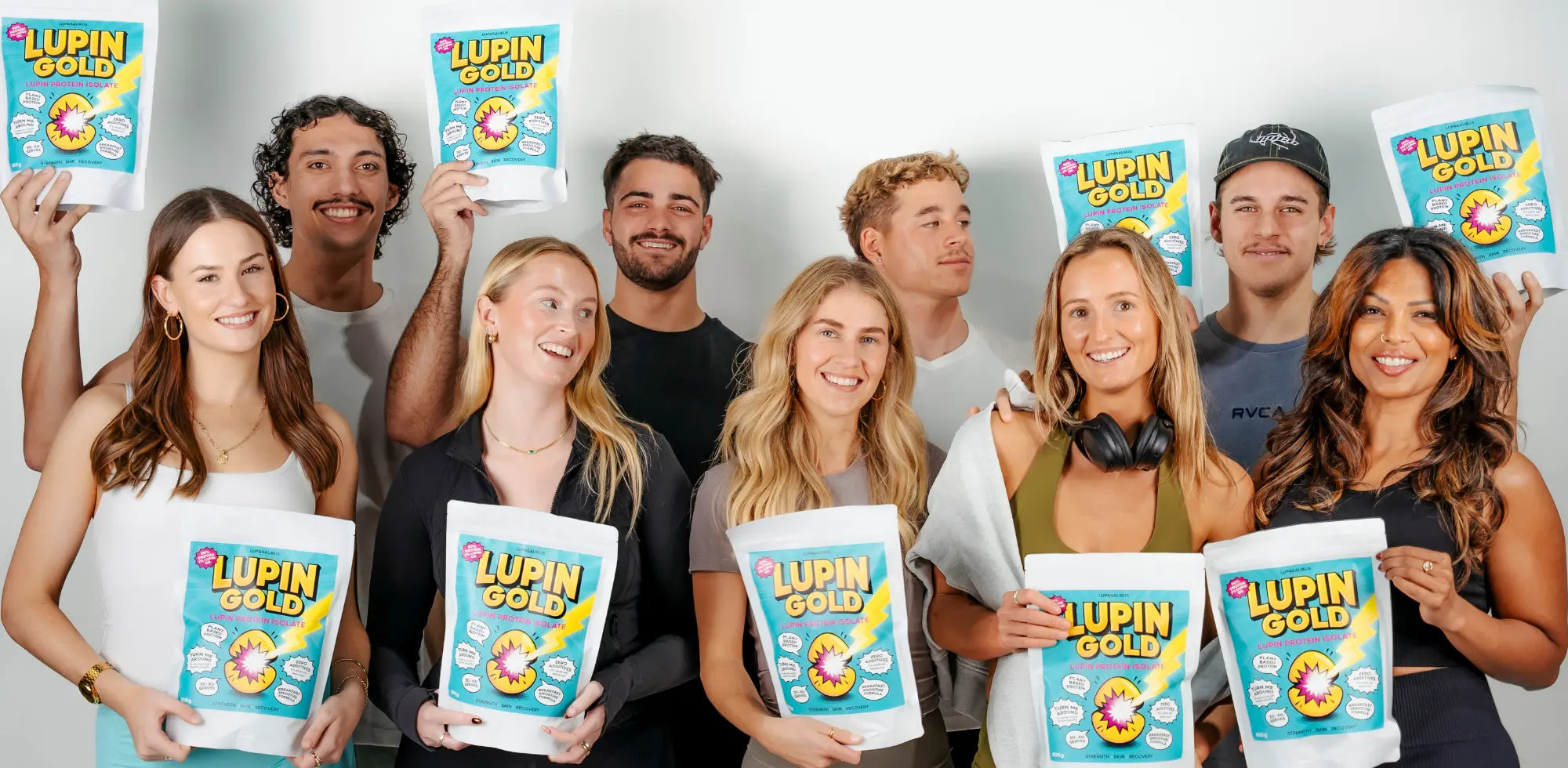 Group of people holding Lupin Gold vegan protein powder packets against a plain background
