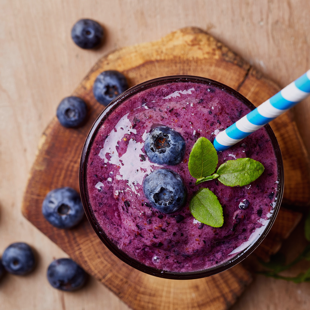 Purple berry and Lupin protein powder smoothie with blueberries and a straw on a wooden surface